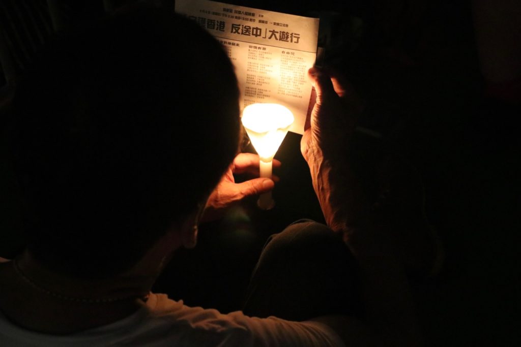 A vigil-goer reads a leaflet featuring a call to join an upcoming rally against a controversial extradition bill. Photo by Samantha Mei Topp.
