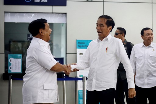 Indonesia’s President Joko Widodo (C) shakes hands with former general Prabowo Subianto (L) at the newly-inaugurated Mass Railway Transport (MRT) system in Jakarta on July 13, 2019, during their first meeting since the April 17 general election. – Defeated Indonesian presidential candidate Prabowo Subianto on July 13 declared a long-overdue congratulation to the incumbent president Joko Widodo for his re-election victory in the highly divisive political contest. (Photo by CHICARITO / AFP)