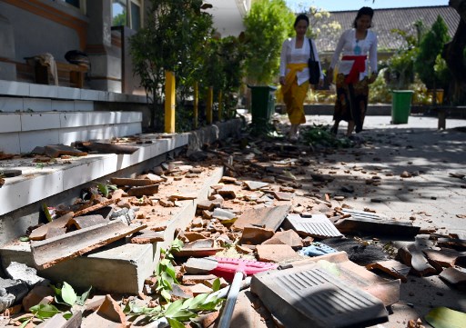 Two teachers walk past tiles which fell off the damaged roof of a school building in Bali after the magnitude-5.8 earthquake that struck off the coast of the island on July 16. (Photo: Sonny Tumbelaka / AFP) 