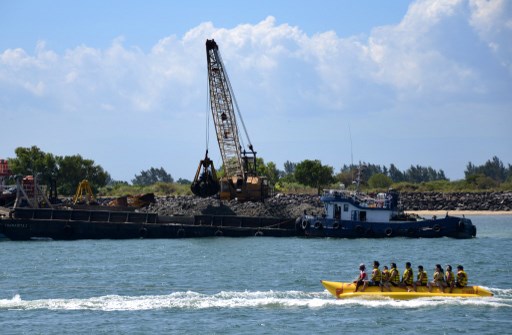A banana boat passes in front a crane dredging a part of Benoa Harbour in Denpasar on Bali island on August 2, 2013. (Photo: Sonny Tumbelaka / AFP) 