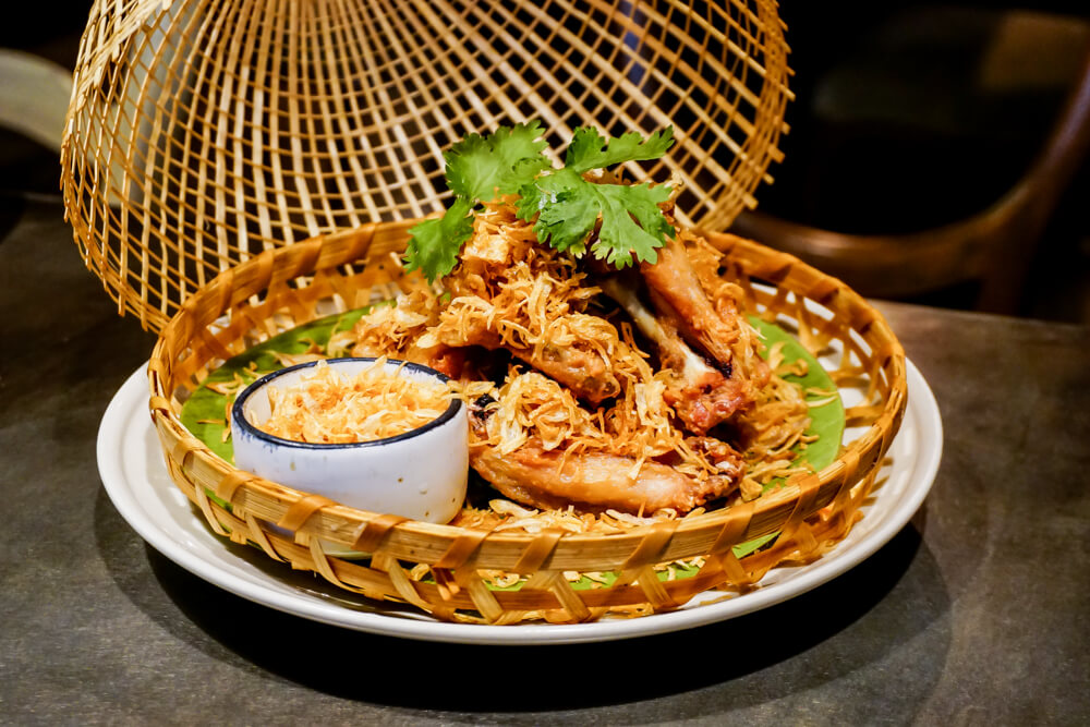 “Peek Gai Tod Nam Pla,” deep-fried chicken wings with fish sauce served with crispy red onions. Photo: Coconuts Media 