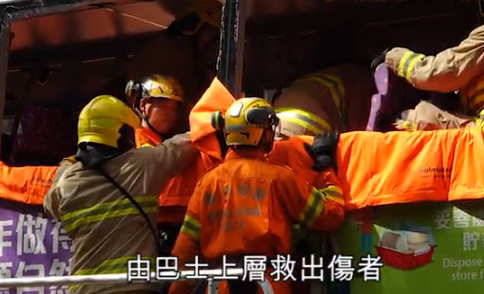 Firefighters help people out of the upper level of a double-decker bus involved in a crash in the New Territories today. Screengrab via Apple Daily video.
