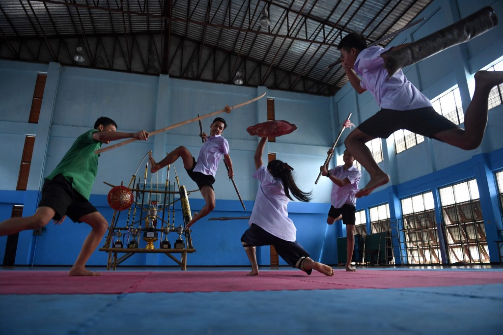 This photo taken on July 8, 2019 shows students practising Krabi Krabong, a Thai martial art, at the Thonburee Woratapeepalarak school in Thonburi, on the outskirts of Bangkok. – Armed with a wooden knife and shield, a teenage girl fends off four sword-wielding boys with high-flying kicks in an action-packed homage to Thailand’s neglected swordfighting tradition. (Photo by Lillian SUWANRUMPHA / AFP)