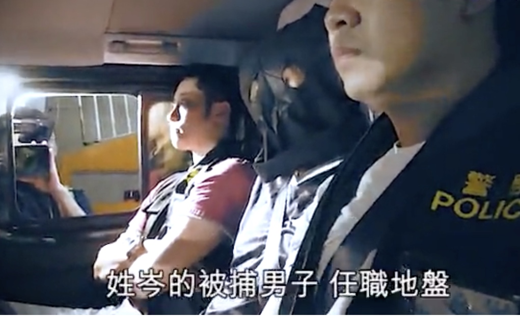 One of the suspects arrested over the protests at police headquarters is transported by police officers last night. Screengrab via Apple Daily Video.