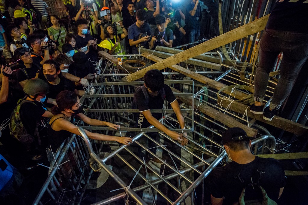 Protesters secure barricades to a gate of the police headquarters in Wan Chai during an unruly protest on June 26. Photo via AFP.
