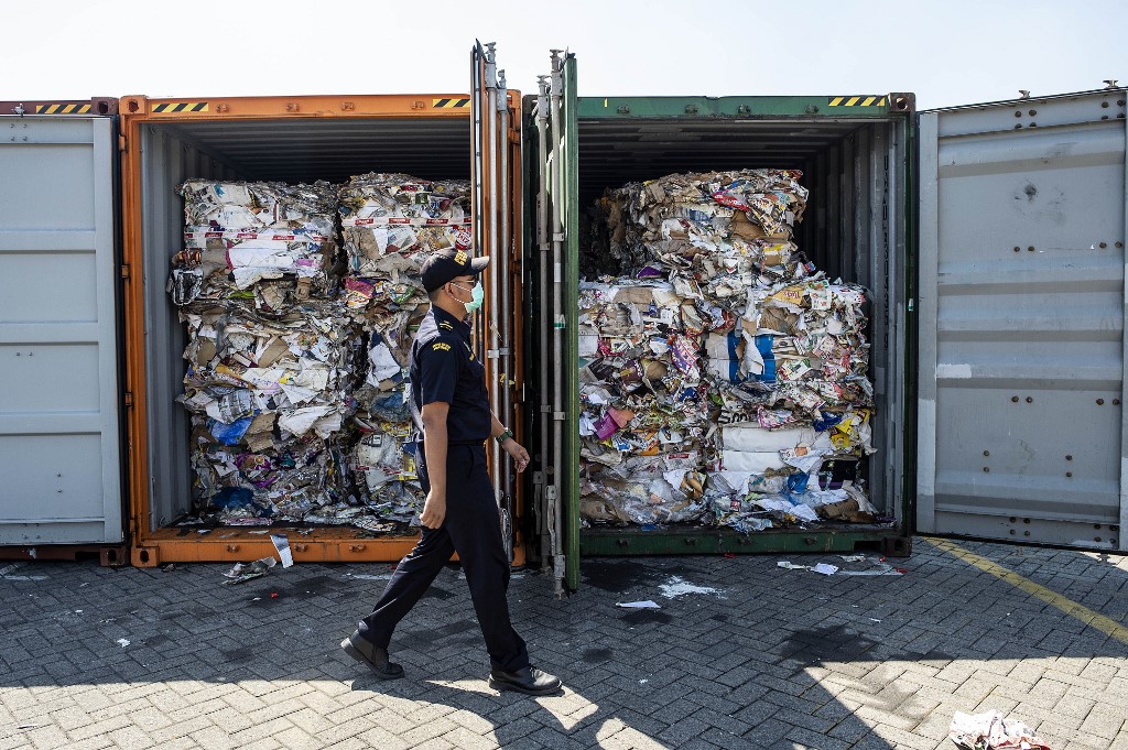 An Indonesian customs officer inspects containers filled with unauthorized trash originating from Australia. Photo via AFP.