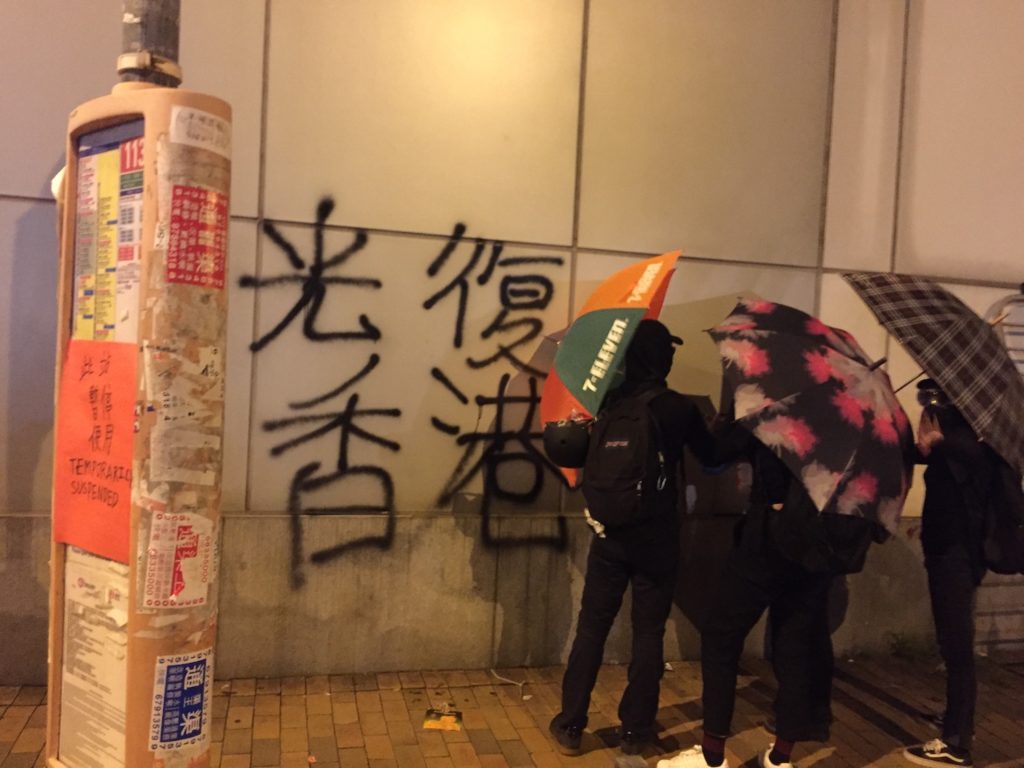 Protesters spray paint graffiti on the wall of the liaison office, the headquarters of the Chinese central government in Hong Kong. Photo by Stuart White.