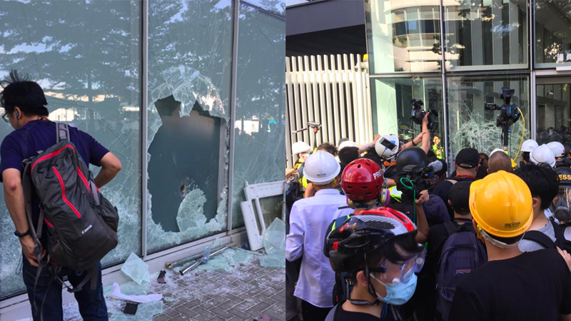 Broken windows outside Hong Kong’s Legislative Council building are examined, while a crowd of protesters remains gathered outside its front doors. Stuart White / Coconuts Hong Kong