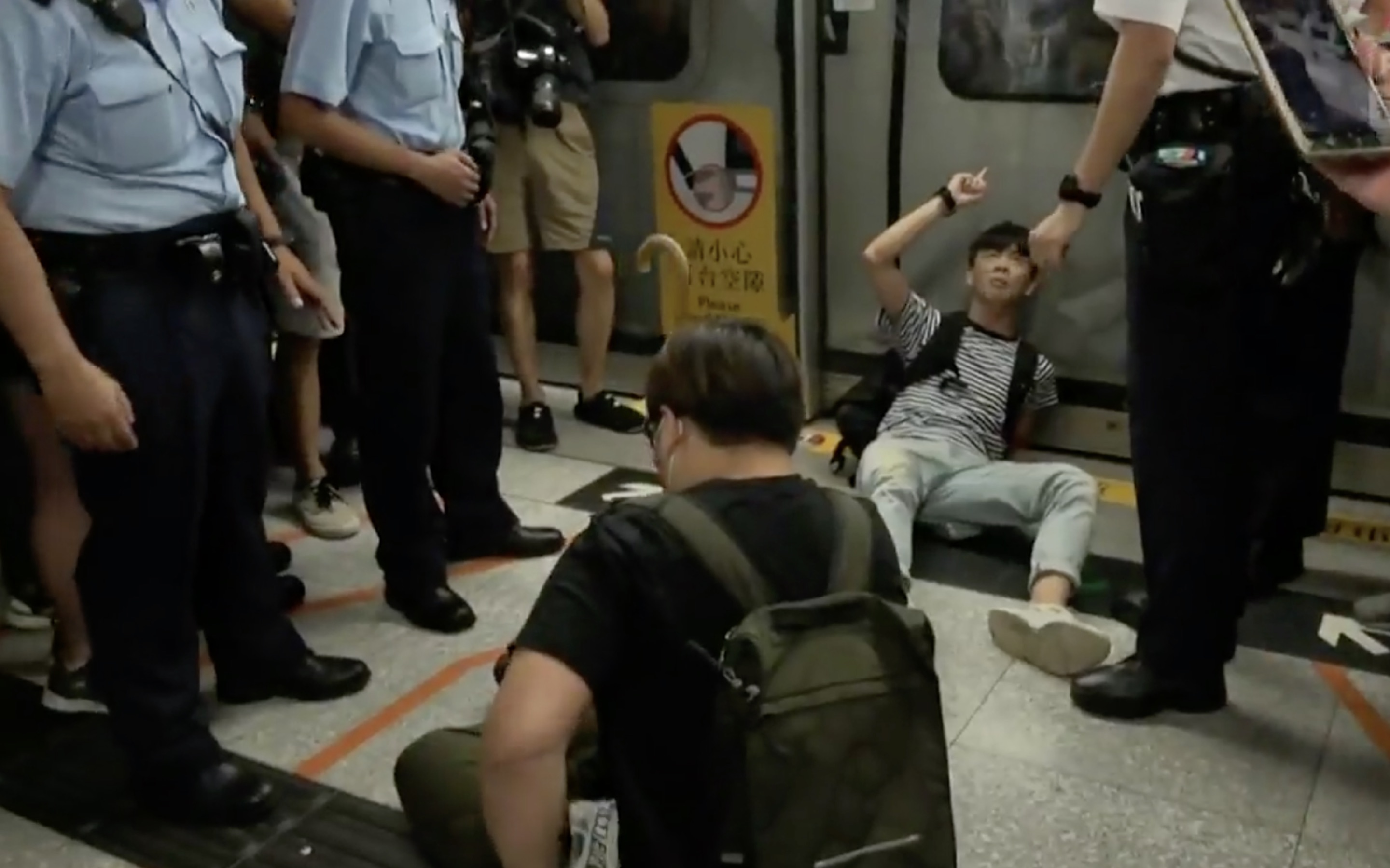 A young protester blocks an MTR train door at Admiralty MTR station. Screengrab via Facebook video/RTHK.