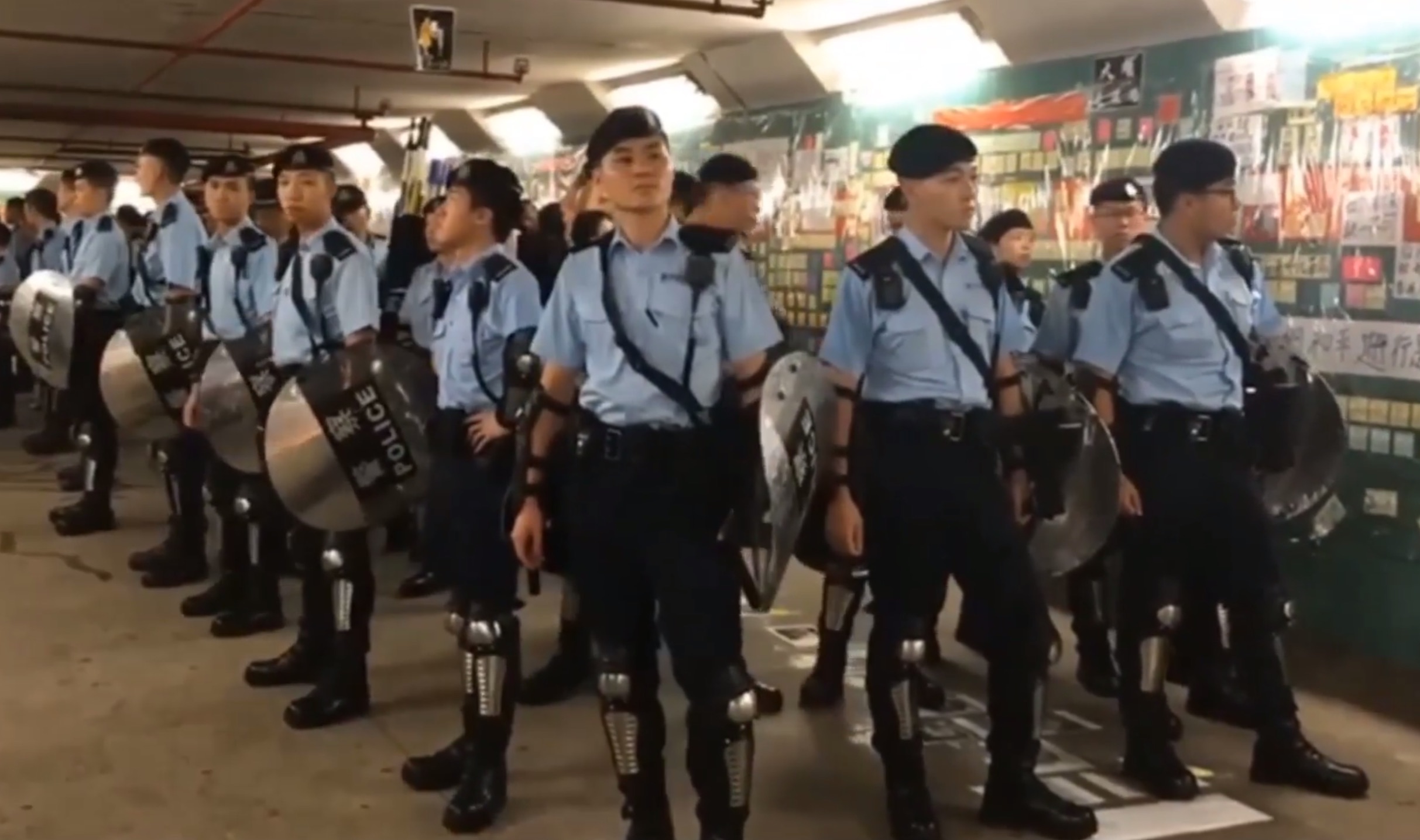 Cops in riot gear secure a pedestrian tunnel in Tai Po where the personal details of an officer were posted. Screengrab via YouTube.
