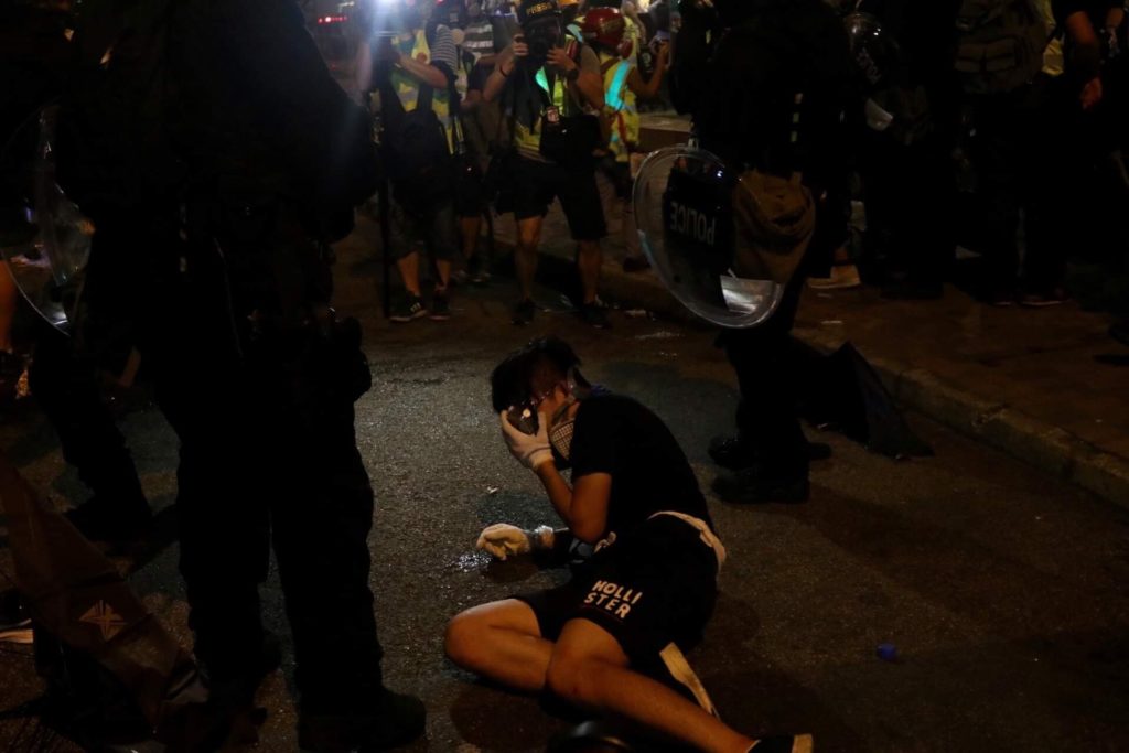 A protester lies on the ground amid a group of riot police during the dispersal of an unsanctioned rally in Yuen Long on Saturday. Photo by Samantha Mei Topp.