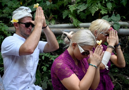 Czech nationals Sabina Dolezalova (center R) and her boyfriend Zdenek Slouka (L) pray ahead of a purification ritual at the Beji Temple, located inside a monkey sanctuary in Ubud on Indonesia’s resort island of Bali on August 15, after a disrespectful online video they posted went viral. Photo:  Sonny Tumbelaka / AFP 