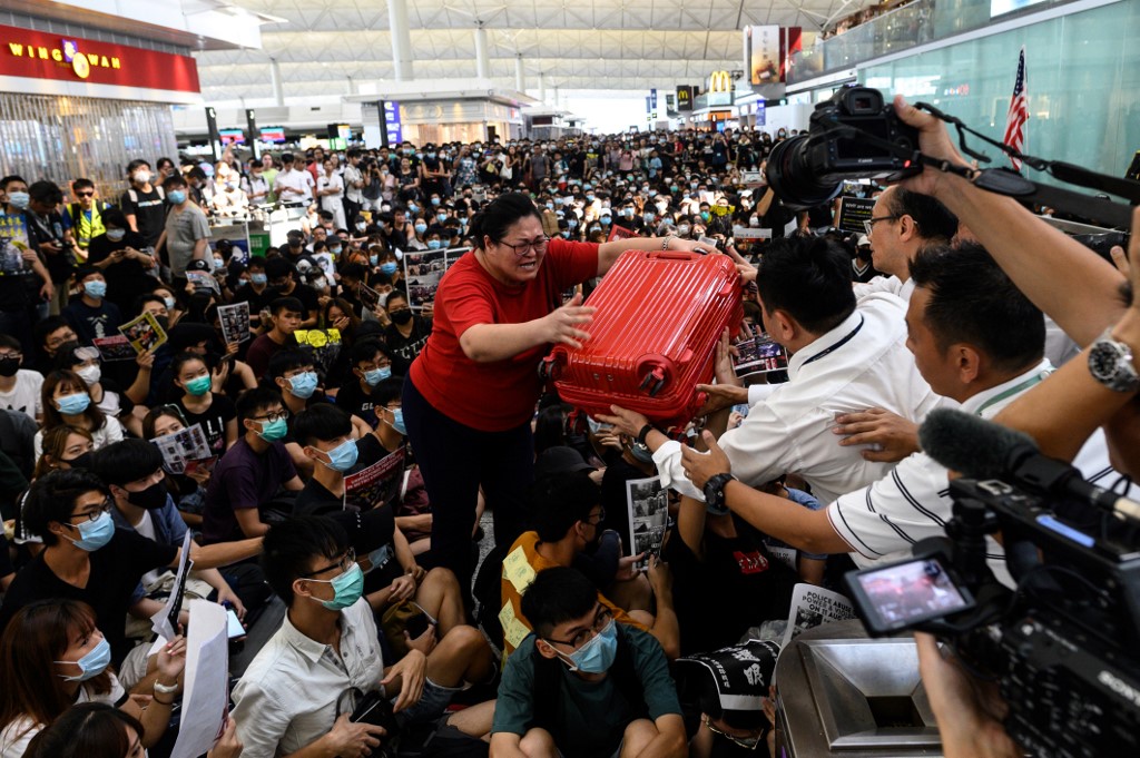 A tourist gives her luggage to security guards as she tries to enter the departures gate during another demonstration by pro-democracy protesters at Hong Kong International Airport on August 13, 2019. File photo via AFP.