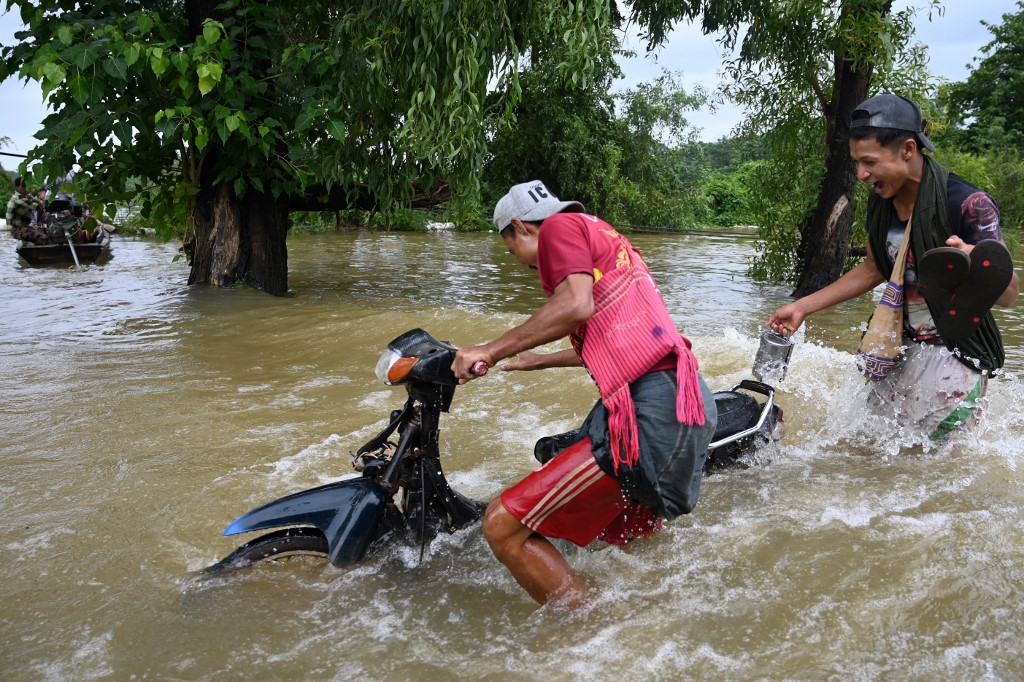 Men push their motorcycle through floodwaters in Shwegyin township, Bago Region on August 8, 2019. Photo by Ye Aung Yhu / AFP