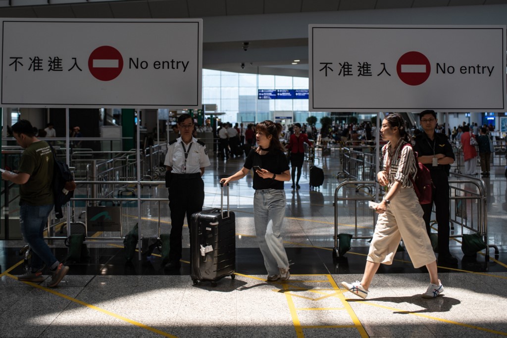 Passengers walk past the arrivals hall of Hong Kong International Airport today after a night of chaos that has prompted reflection in the protesters’ camp. Photo via AFP.