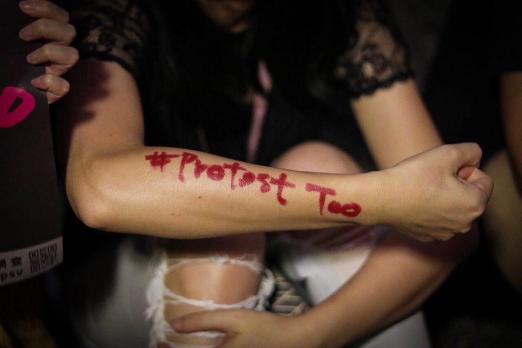 A protester with the phrase '#ProtestToo' written on her arm in lipstick at a rally against the alleged sexual harassment of female protesters by police. Photo by Samantha Mei Topp.