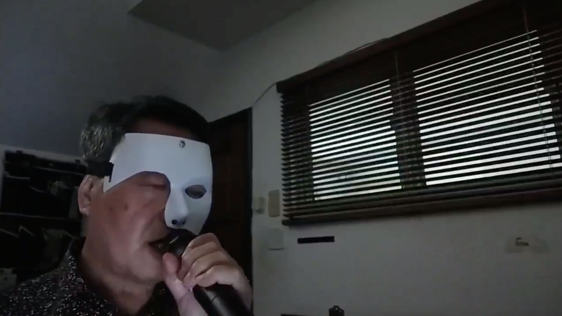 Screenshot of video showing a half-masked Tan Kin Lian singing to Phantom of the Opera’s Music of the Night. 