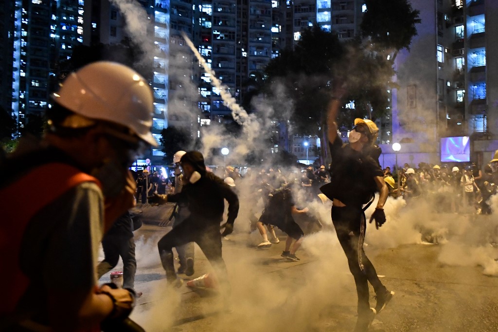 Protesters throw back tear gas fired by the police in Wong Tai Sin during a general strike in Hong Kong on August 5, 2019. Photo via AFP.