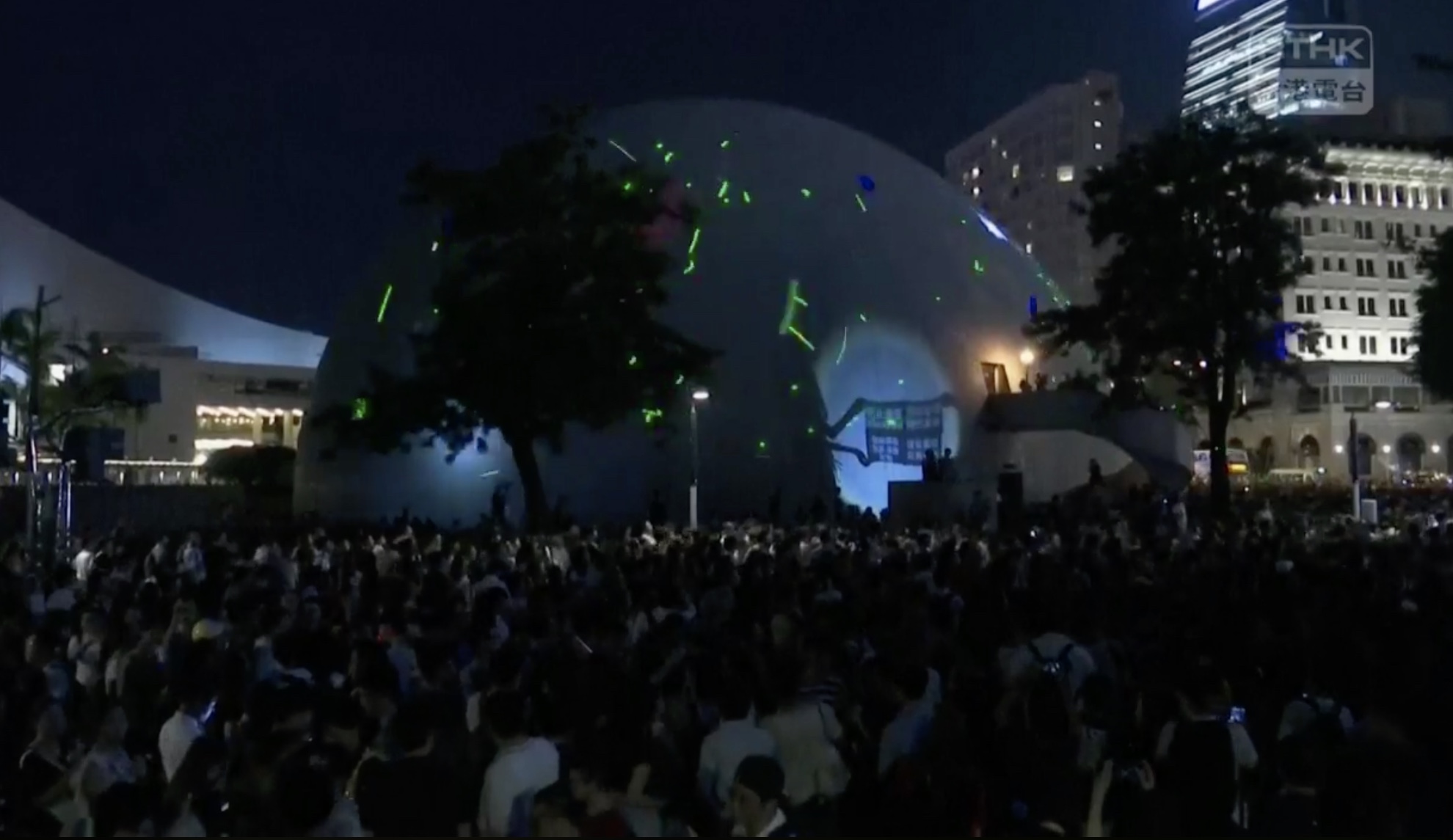 Hongkongers shine laser pointers on the side of a planetarium in Tsim Sha Tsui in protest of the arrest of a student leader for possessing laser pointers. Screengrab via RTHK livestream.