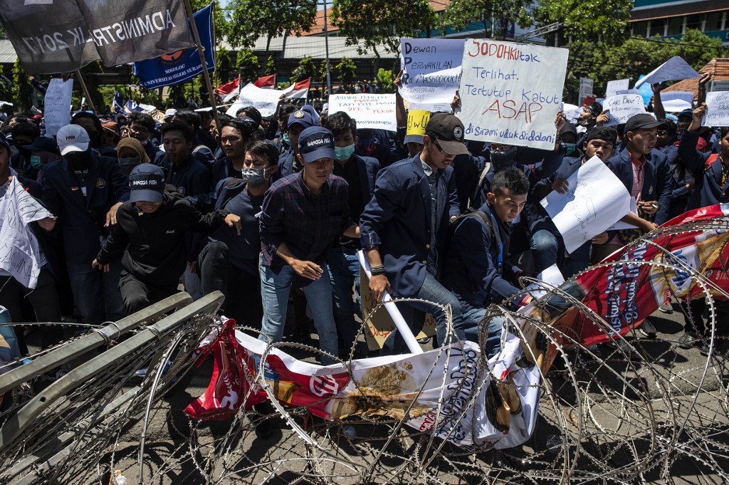 Student protesters step on barbed wire during a rally in Surabaya, East java province, on September 25, 2019, against the government's proposed change in its criminal code laws and plans to weaken the anti-corruption commission. (Photo by JUNI KRISWANTO / AFP)