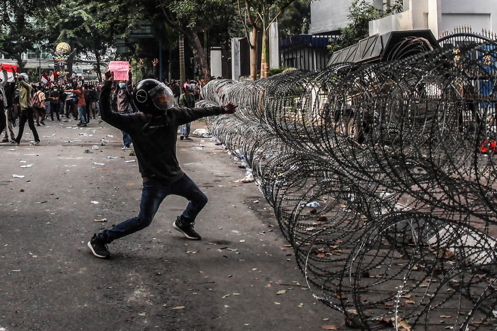 An Indonesian student throws a rock to the police during a rally against divisive legal reforms, in front of a parliament building in Medan, North Sumatra, on September 27, 2019. – A second Indonesian student protester died from injuries sustained during a wave of nationwide demonstrations against divisive legal reforms, including banning pre-marital sex and weakening the anti-graft agency, officials said. (Photo by ALBERT IVAN DAMANIK / AFP)
