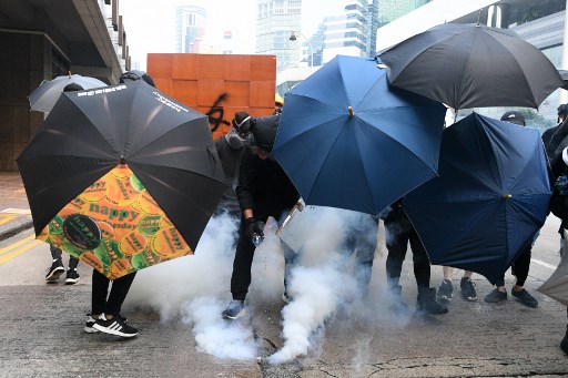 Protesters react by putting water on a tear gas canister fired by Hong Kong police during clashes following an unsanctioned march through Hong Kong on September 29, 2019. – Thousands of Hong Kongers defied police tear gas rounds on September 29 to hold an unsanctioned march through the city, part of a coordinated day of global protests aimed at casting a shadow over communist China’s upcoming 70th birthday. (Photo by Mohd RASFAN / AFP)