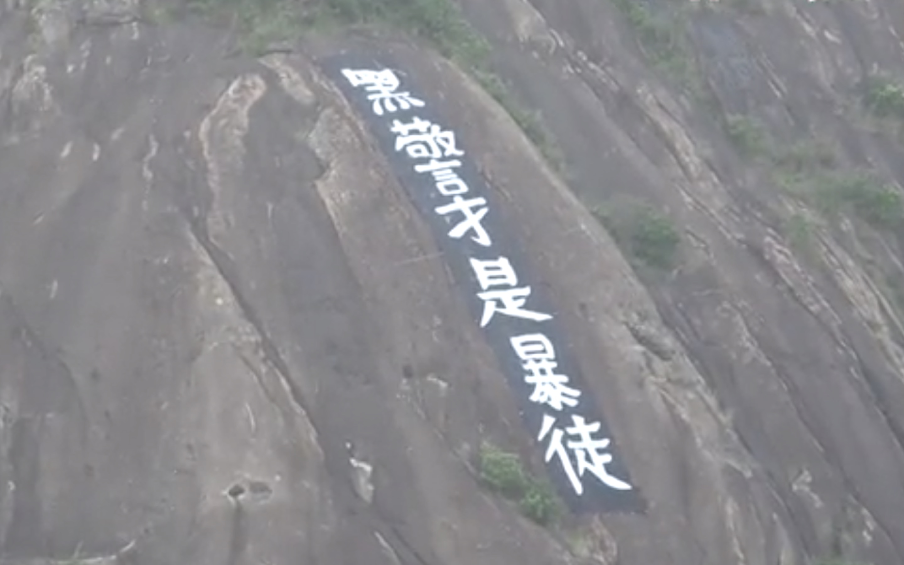 A banner reading ‘dirty cops are rioters’ was unfurled on the side of Devil’s Peak last night. Screengrab via Apple Daily video.