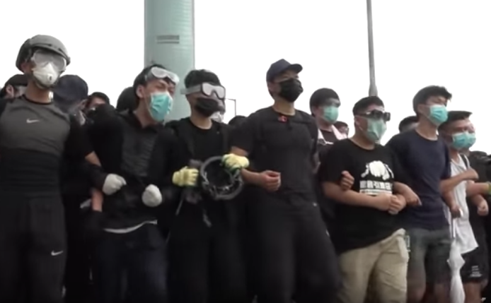 Protesters lock arms and sing “Glory to Hong Kong,” a new anthem created for the protest movement. Screengrab via YouTube