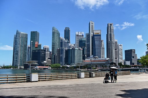 This photograph taken on May 6, 2019, shows people walking near the central business district in Singapore. (Photo by Roslan RAHMAN / AFP)