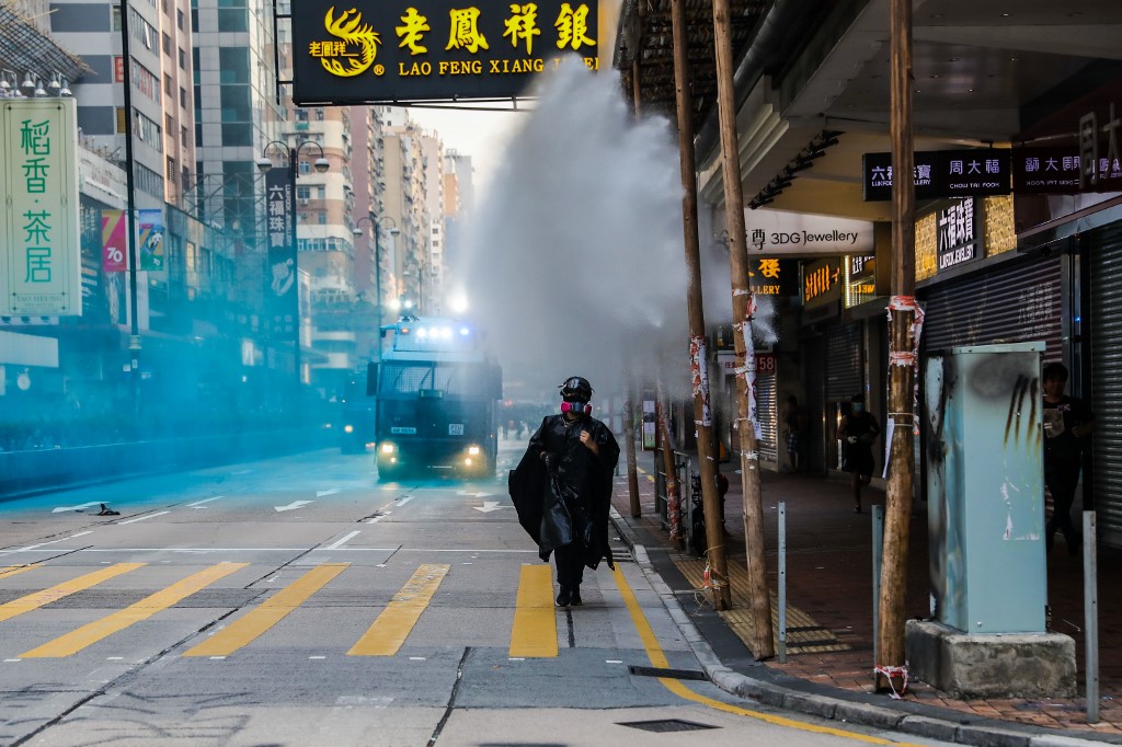 A protester runs from advancing police as they deploy a water cannon on a road in the Tsim Sha Tsui district in Hong Kong on October 20, 2019. – Police fired water cannon and tear gas at Hong Kongers who defied authorities with an illegal march on October 20, their numbers swollen by anger over the recent stabbing and beating of two pro-democracy protesters. (Photo by DALE DE LA REY / AFP)