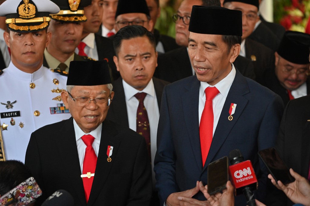 Indonesian President Joko Widodo (R) speaks to journalists with new Vice President Ma’ruf Amin (L) after their inauguration at the parliament building in Jakarta on October 20, 2019. – Indonesia’s President Joko Widodo was sworn in for a second term on October 20, as helicopters flew overhead and troops kept watch in the capital Jakarta — days after Islamist militants tried to assassinate his top security minister. (Photo by ADEK BERRY / POOL / AFP)