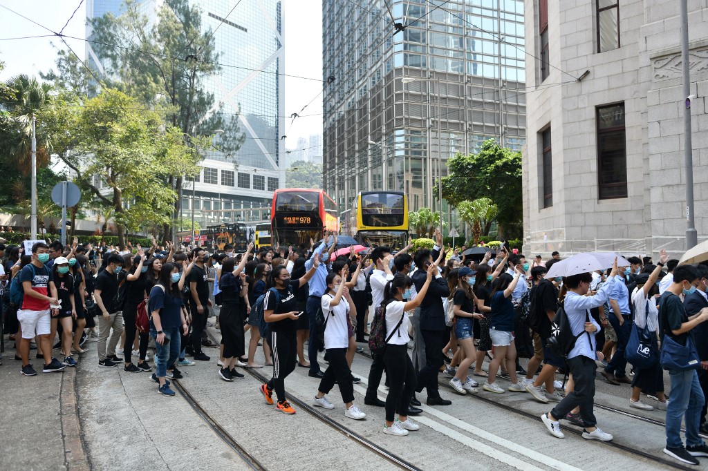 Protesters, many of them office workers, take part in an impromptu demonstration in Central today, one day after a teenage protester was shot by police during an unruly protest. Photo via AFP.