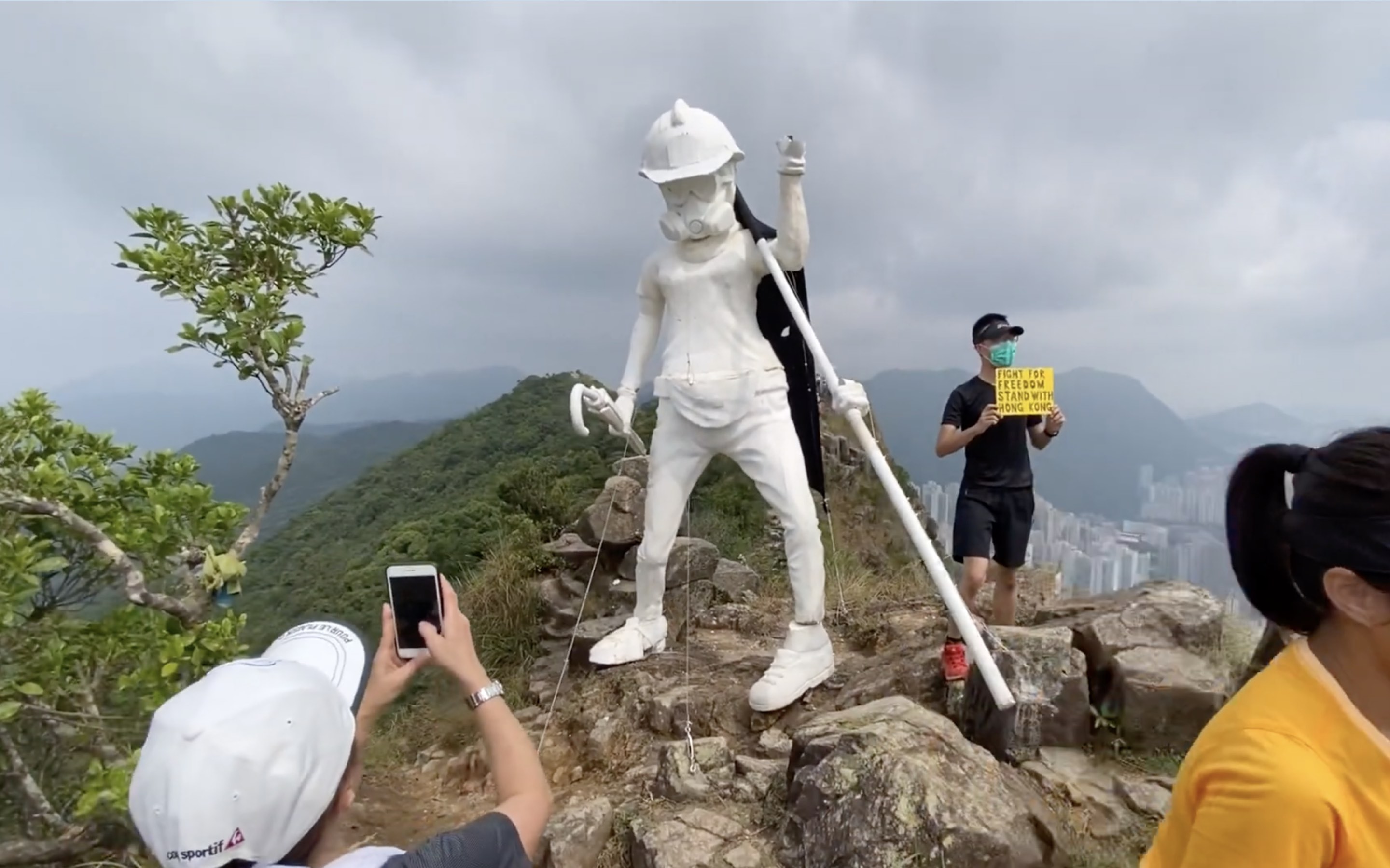 Hikers grabbing a photo with Lady Liberty Hong Kong. Screengrab via YouTube.