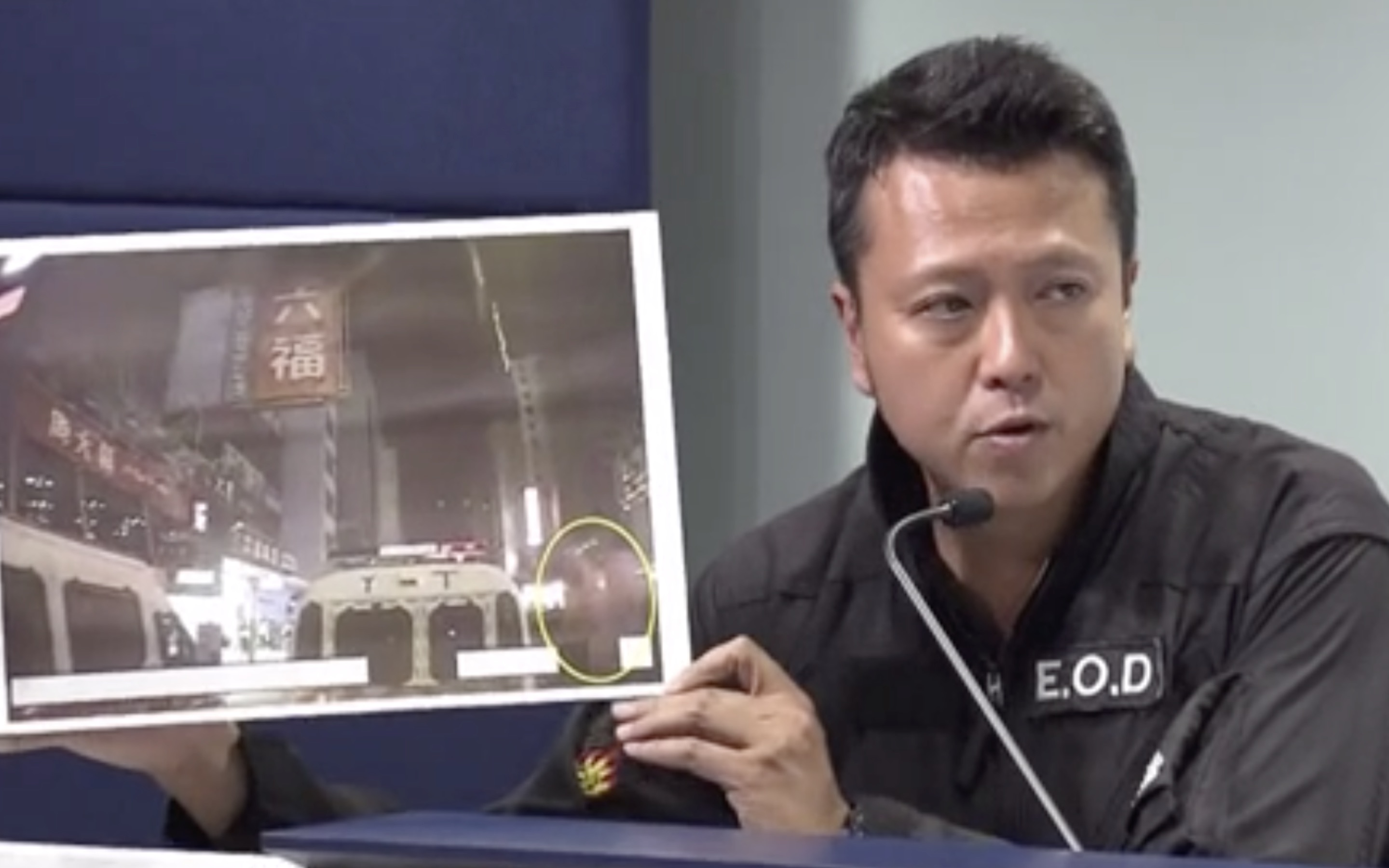 Superintendent Suryanto Chin-chiu of Explosive Ordinance Disposal Bureau holds up a photo of what they say was an explosion created through a remote-controlled device. Screengrab via Facebook/Now News.