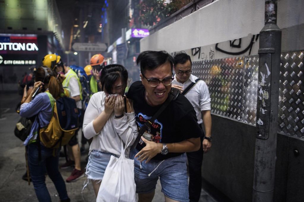Bystanders react after police fired tear gas to disperse residents and protesters in the Mong Kok district of Kowloon in Hong Kong on October 27, 2019. Photo via AFP.