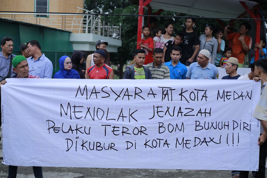 Indonesian residents hold a banner that reads “residents of Medan city reject the body of suicide bomber to be burried in Medan city”, in Medan on November 18, 2019. – Indonesian authorities rounded up at least 45 terror suspects in a nationwide dragnet after a lone-wolf terrorist linked to Islamic State (IS) blew himself at a police station on Sumatra island last week, officials said on November 18. (Photo by GATHA GINTING / AFP)