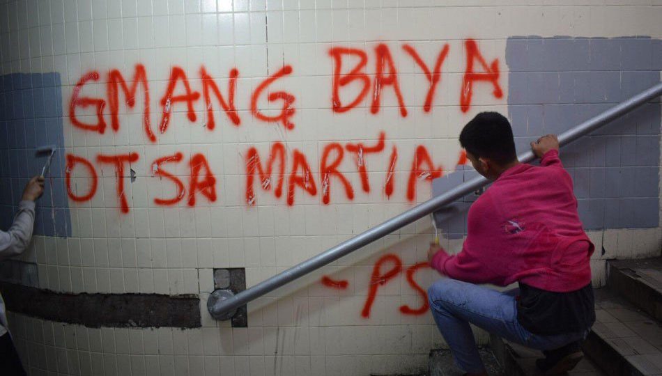 A man paints over anti-government slogans painted on the newly-cleaned Lagusnilad. <i></noscript>Photo: Manila Public Information Office</i>