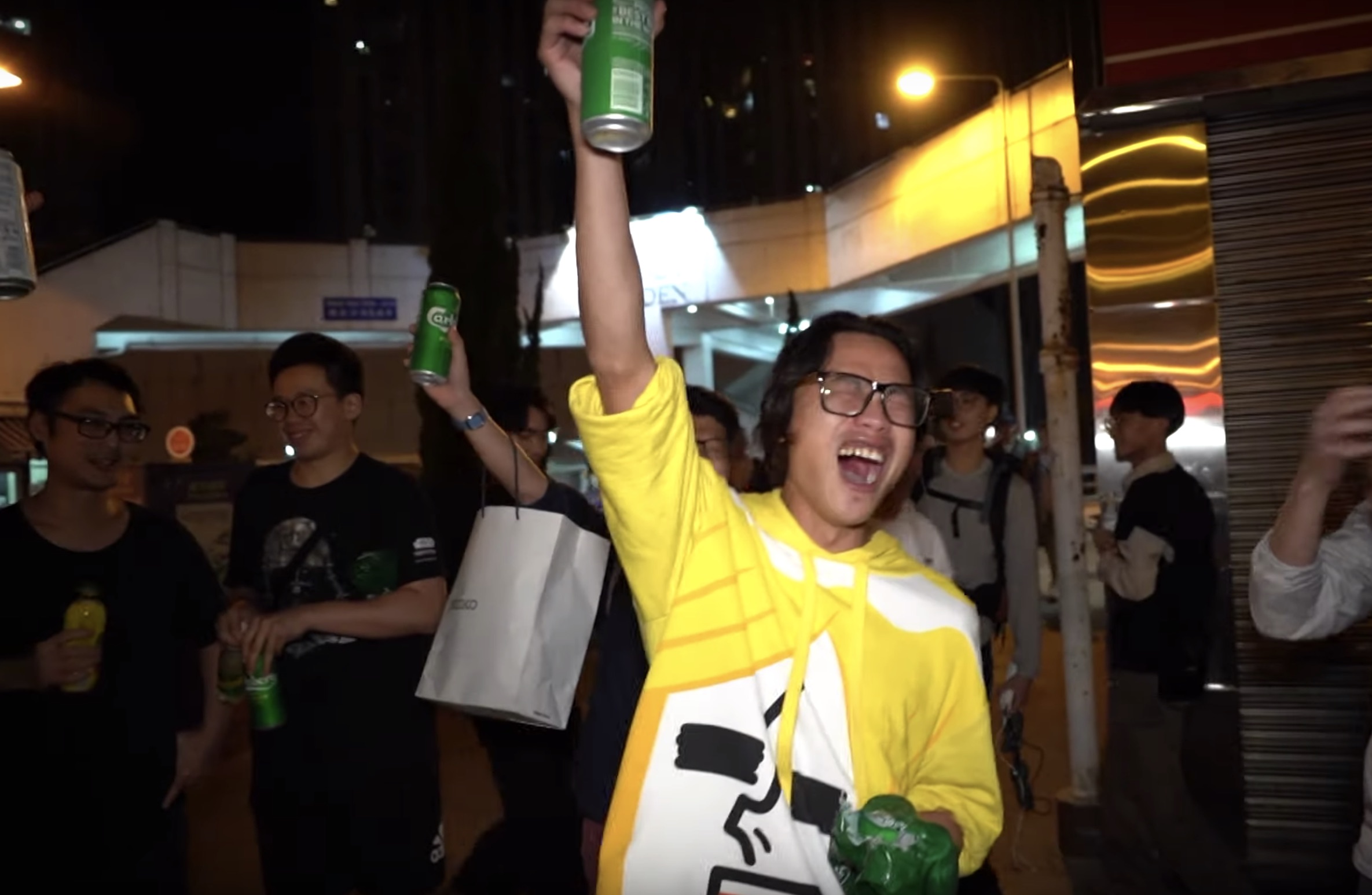 A man raises a beer with others in Tuen Mun after controversial politician Junius Ho loses his district council re-election bid last night. Screengrab via YouTube.
