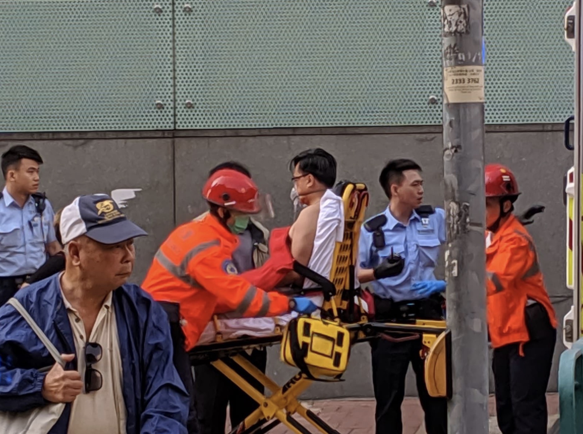 Pro-Beijing lawmaker Junius Ho being taken away in an ambulance after being stabbed while canvassing in Tuen Mun. Photos via Twitter/Galileo Cheng.