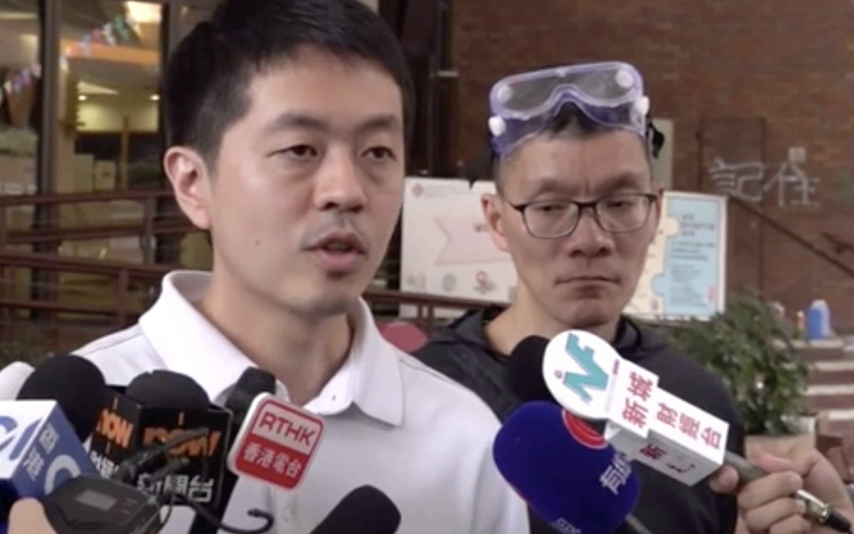 Pro-democracy lawmaker Ted Hui speaking to reporters ahead of him and dozens of protesters at Polytechnic University surrendering. Screengrab via Facebook.