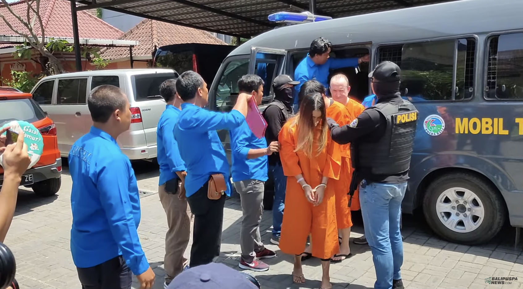 Singaporean Ruth Tan En Yi, looking down in orange, stands cuffed in an orange prison jumpsuit. Photo: BaliPuspaNews/YouTube
