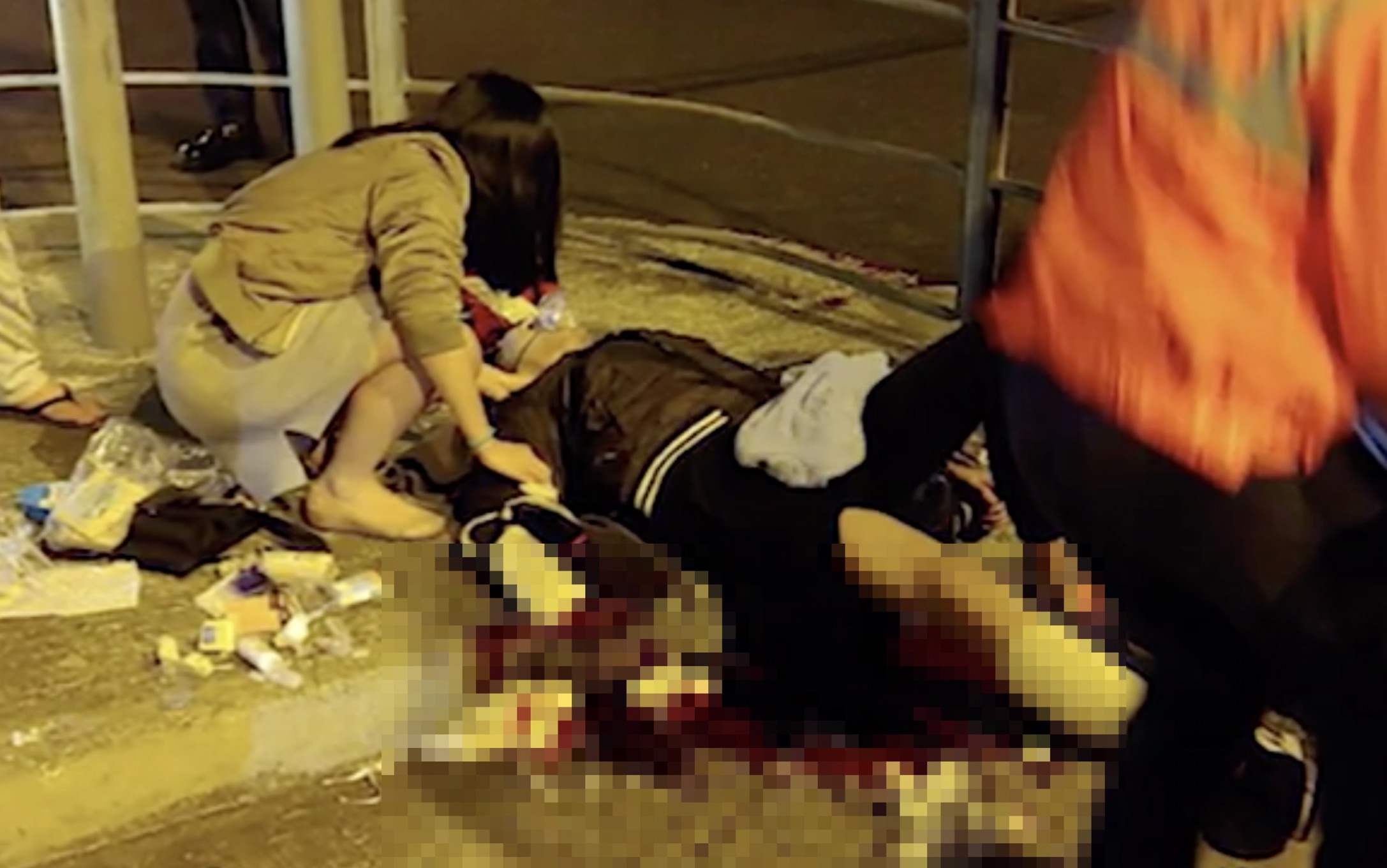 District councillor and doctor Kwong Po-yin tending to a 23-year-old man who was attacked by two knife-wielding men. Screengrab via Apple Daily video.