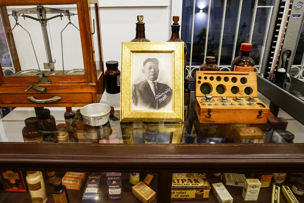A portrait of Boonmee “Moh Mee” Kasemsuwan along with his drug store’s items inside the house.