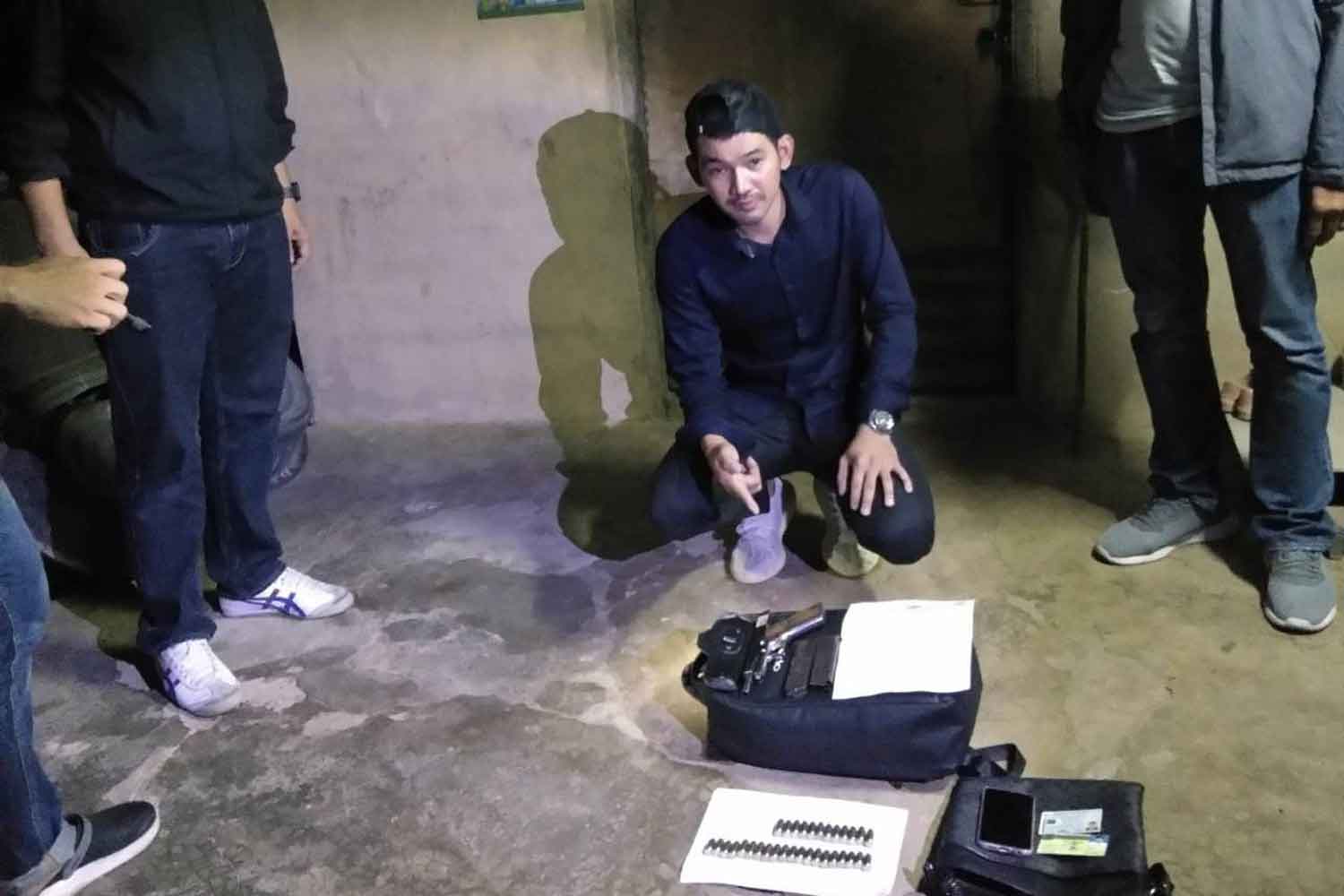 
Danusorn Noomcharoen points to weapons and ammunition early Wednesday morning inside his Phetchaburi province home, where he was arrested on suspicion of killing his ex-wife inside a Bangkok shopping mall. 
