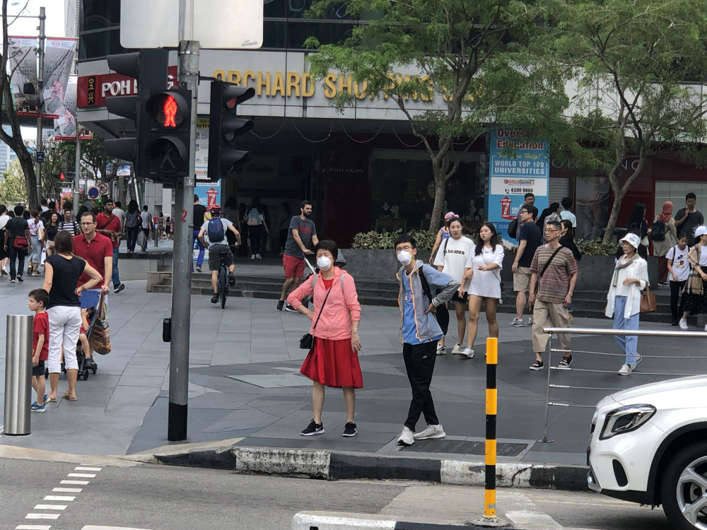 Pedestrians wearing masks cross Singapore’s Orchard Road. Photo: Coconuts Media