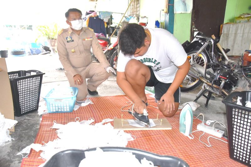 Police oversee a “re-enactment” of the recycled mask cottage industry going on north of Bangkok in Saraburi province.
