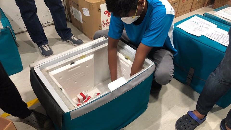 Members of the Research Institute for Tropical Medicine unload  test kits donated by China to be delivered to subnational testing labs on Saturday <i></noscript>Photo: Department of Health / FB </i>