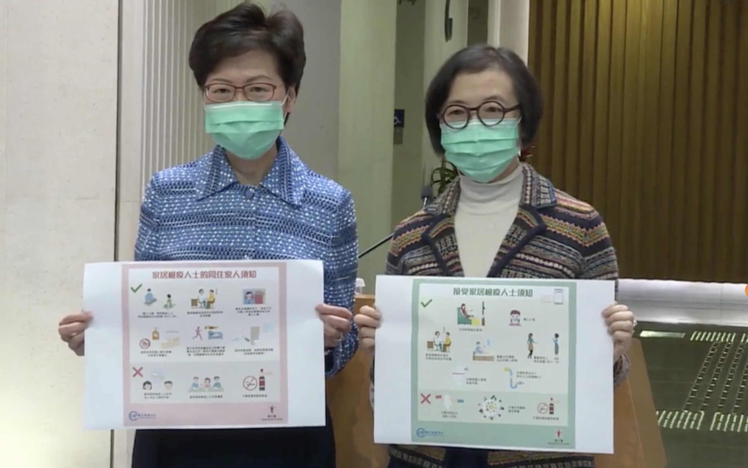 Chief Executive Carrie Lam and Health Secretary Sophia Chan hold up new posters for people under home quarantine. Screengrab via Facebook video/i-Cable.