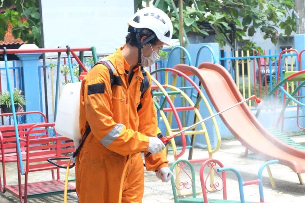 A worker disinfecting a children’s playground in Indonesia. Photo: Dompet Dhuafa