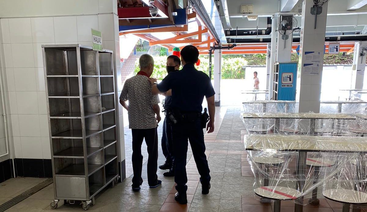 Two police officers confront an elderly man at a hawker center in a photo dated April 9, 2020. Photo: Masagos Zulkifli/Facebook